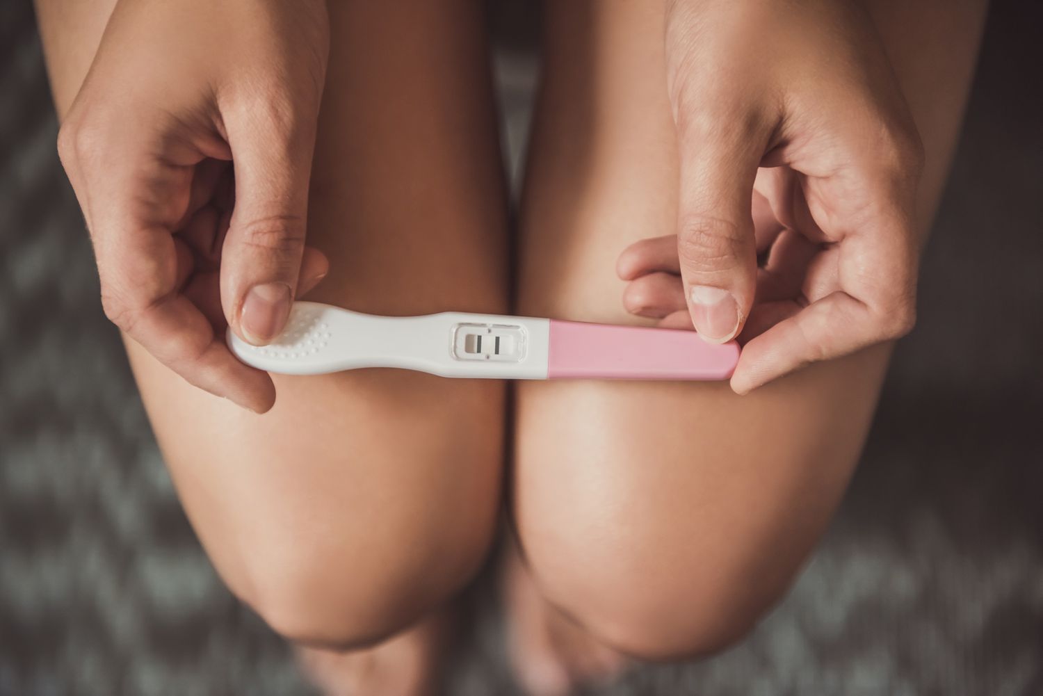 Femme tenant un test de grossesse sur les genoux