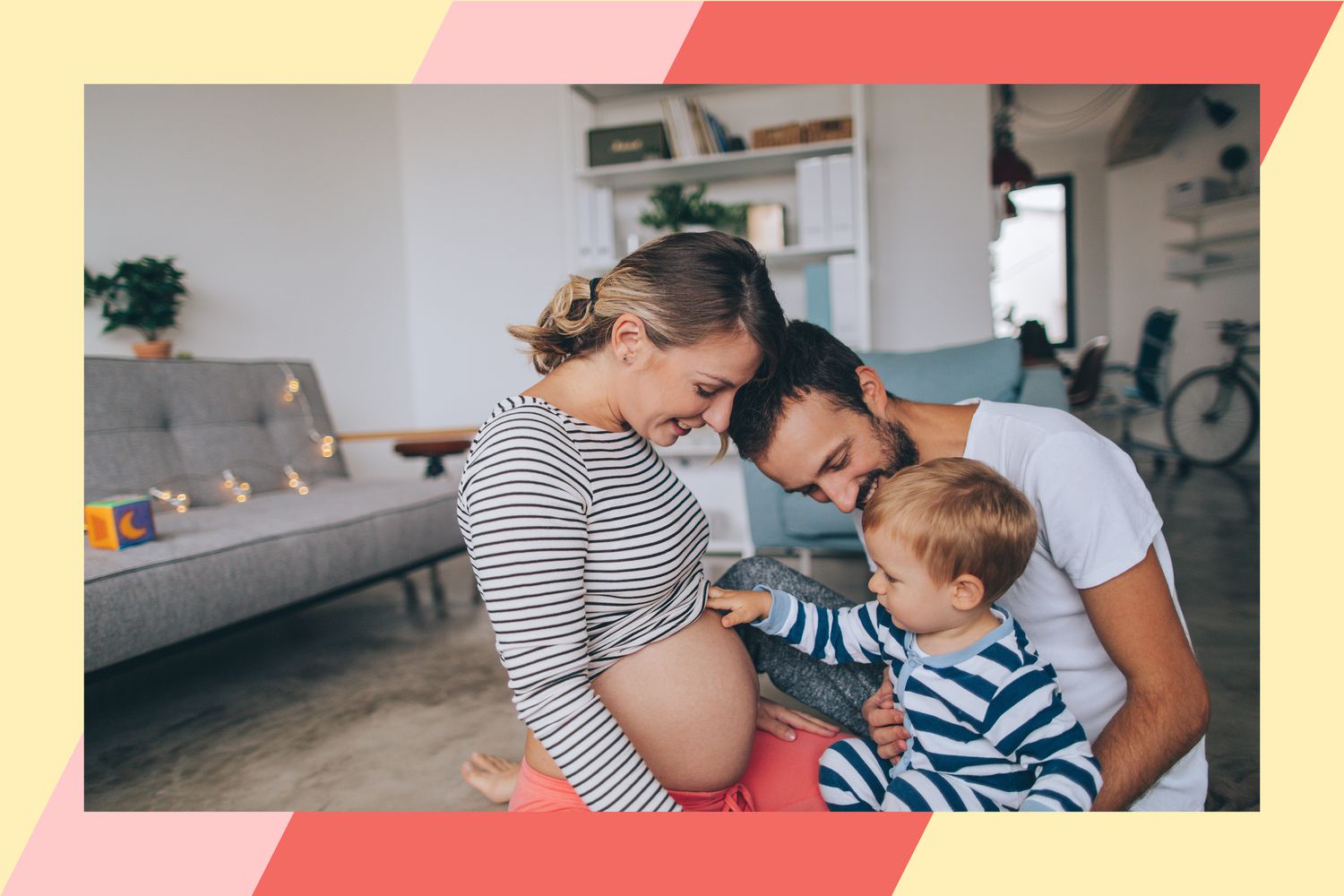 Un enfant assis sur les genoux de son père en touchant le ventre de sa mère enceinte