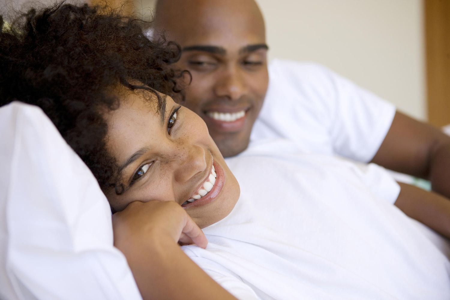 Jeune couple souriant au lit